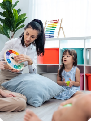 Female teacher showing a colorful educational tool to a young girl